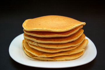 Piled up sweet, delicious pancakes on a white plate 