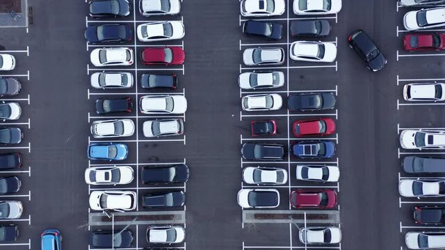 Aerial top view of many cars parked. Drone View over Outdoor Parking Lots. Car finds parking spot. Car parking of a shopping center, top-down aerial shooting. 