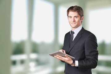Smiling mature businessman in an office. Businessman looking at the camera while standing alone in a modern workplace.