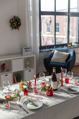 winter holidays, dinner party and celebration concept - christmas table serving with candles, crockery and wine at home