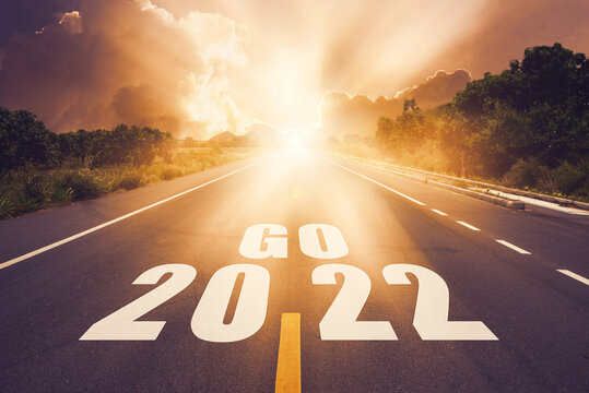 Start to New year 2022 concept. Go 2022 written on highway road in the middle of empty asphalt road with sunset or sunrise light above asphalt road.