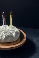 food, sweets and objects concept - close up of meringue or zephyr birthday cake with four candles on wooden stand with eucalyptus branch over dark background