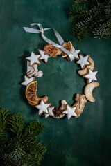 Obraz na płótnie Canvas Christmas cookies wreath on table , green background, xmas decoration, tree branch . Vertikal view