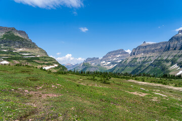 Fototapeta na wymiar View from Logan Pass in Glacier National Park, Montana on a sunny summer day, with glacial valley, snow-capped mountains, alpine lakes, and grass