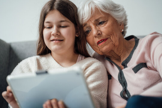 Granddaughter using tablet PC with grandmother at home