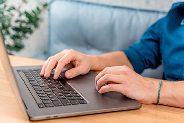 The hands of a young man on a laptop keyboard at home or in a cafe. Remote work or shopping online. Freelance and freedom.