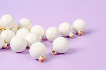 White Christmas balls lie on a purple background, a beautiful minimalistic background for Christmas and New Year