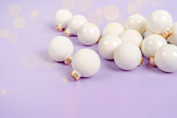 White Christmas balls lie on a purple background, a beautiful minimalistic background for Christmas and New Year