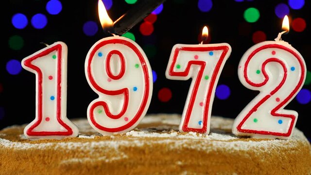 Birthday cake with white burning candles in the form of number 1972