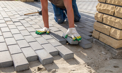 A worker is laying paving slabs in the yard. Construction
