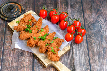
 Crispy  deep fried   chicken strips and wedges potato. Breaded  with cornflakes chicken  breast fillets  with chilly peppers and fresh   basil on wooden rustic background