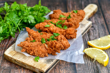 
 Crispy  deep fried   chicken strips and wedges potato. Breaded  with cornflakes chicken  breast fillets  with chilly peppers and fresh   basil on wooden rustic background