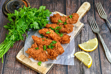 
 Crispy  deep fried   chicken strips and wedges potato. Breaded  with cornflakes chicken  breast fillets  with chilly peppers and fresh   basil on wooden rustic background