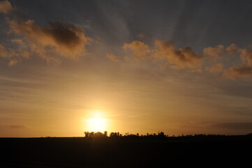 Sunset at dusk in the evening with trees, clouds and orange sky in Normandy, northern France