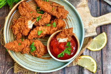 
 Crispy  deep fried   chicken strips and wedges potato. Breaded  with cornflakes chicken  breast fillets  with chilly peppers and fresh   basil on wooden rustic background