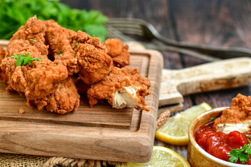 
 Crispy  deep fried   chicken strips and wedges potato. Breaded  with cornflakes chicken  breast fillets  with chilly peppers and fresh   basil on wooden rustic background