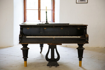 Old piano in a white room with window