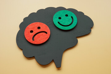 Bipolar disorder concept. Brain shape with happy and sad emoticons. - obrazy, fototapety, plakaty
