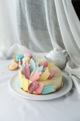 Beautiful festive cake with pink, yellow and turquoise cream and teapot on the table