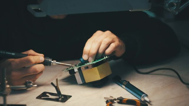 man is fixing a electronic power unit with a soldering