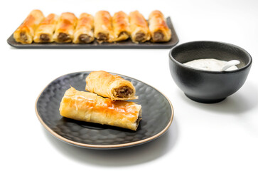 Meat rolls pastry - fried minced pork meat in spring rolls in a black oval plate, isolated on white background with clipping path included