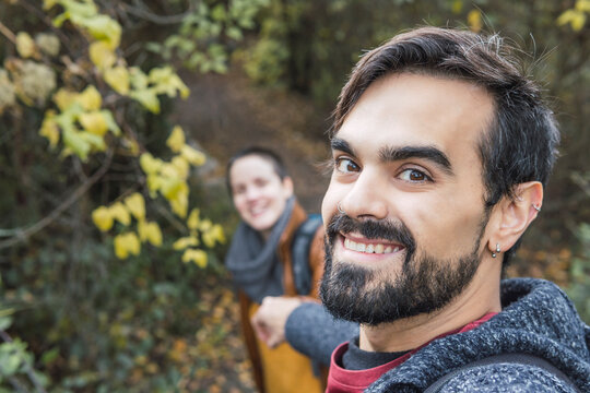 Smiling handsome man with girlfriend hiking in forest