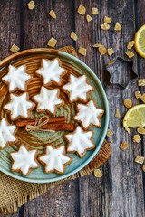 Gingerbread star shaped   cookies and cinnamon sticks    on   wooden background with lights . Christmas  card background  . Holiday wallpaper