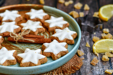 Gingerbread star shaped   cookies and cinnamon sticks    on   wooden background with lights . Christmas  card background  . Holiday wallpaper