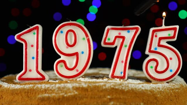 Birthday cake with white burning candles in the form of number 1975