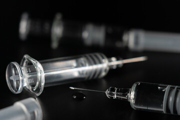 Close view of the glass syringes on a black background. Medicine and health concept. Vaccine against viruses. Needle and drugs. Selective focus. Copy space