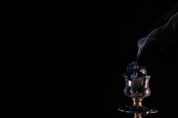 An extinguished candle. Smoke. Stands in an old brass metal candlestick. Black background. Vintage...