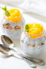 Healthy Chia Pudding with Coconut Milk, mango, chia seeds, granola in a Glass. Concept of healthy eating, healthy lifestyle, dieting, fitness menu. 