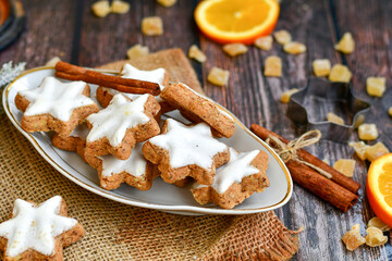 Traditional German bread   Christmass stollen  cake ,gingerbread star shaped   cookies and cinnamon sticks    on   wooden background with lights . Christmas  card background  . Holiday wallpaper