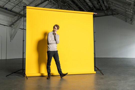 Businessman in front of backdrop at industrial hall