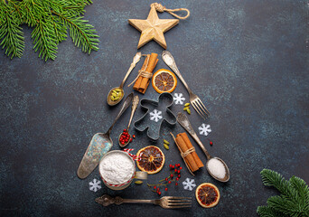 Christmas and New Year baking composition made in shape of Christmas fir tree from kitchen tools and cooking ingredients on dark blue stone concrete background table top view flat lay