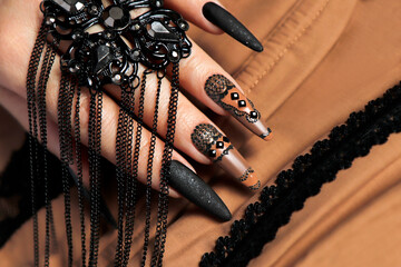 Nail design with black and beige nail polish with rhinestones.
