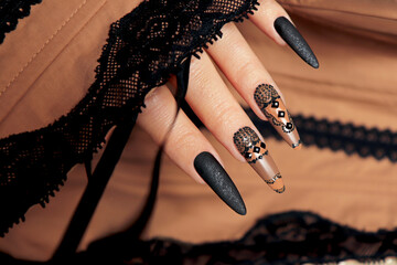Nail design with black and beige nail polish with rhinestones.