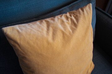 gelbes Kissen gemütlich auf einer grauen Couch drapiert