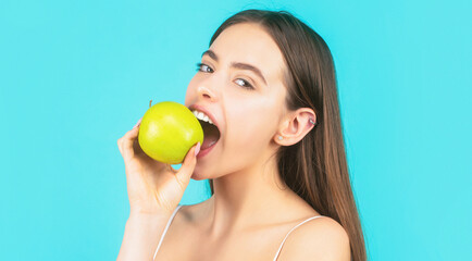 Woman eat green apple. Portrait of young beautiful happy smiling woman with green apples. Healthy diet food. Stomatology concept. Woman with perfect smile holding apple, blue background