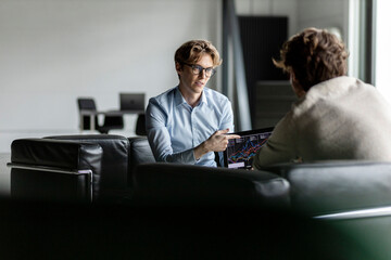 Young businessman explaining business plan to colleague in lobby