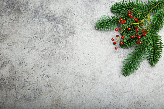 Christmas and New Year flat lay composition frame with green fir tree branch and forest red berries on gray stone concrete background with free space for your text