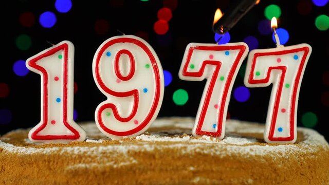 Birthday cake with white burning candles in the form of number 1977