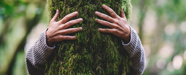 Nature lover hugging trunk tree with green musk in tropical woods forest. Green natural background. Concept of people love nature and protect from deforestation or pollution or climate change - obrazy, fototapety, plakaty
