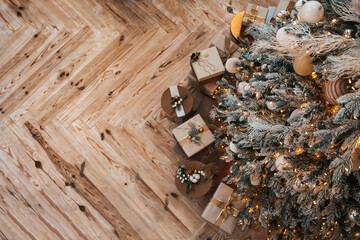 Christmas tree with gifts on the wooden floor. Top view. Festive Christmas background with copy space. Soft focus.