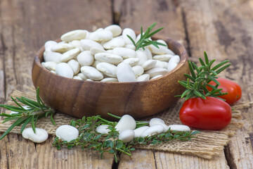 white beans, tomatoes and herbs on wooden background