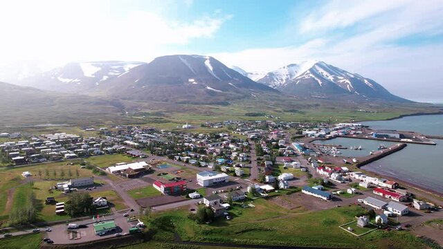 Vibrant aerial shot of coastal town in Iceland. Shot turns and reveals ocean. Beautiful clear day with bright sun.