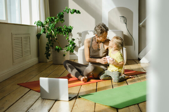 Mother and daughter talking on exercise mat
