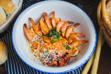 Traditional bright shrimp risotto in a bowl on a table in a restaurant with a beautiful decor in a dark key close-up.