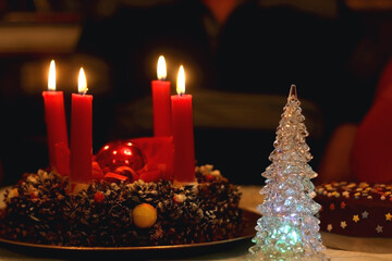 Advent wreath with four lit candles and Christmas decoration on a holiday table. Selective focus.