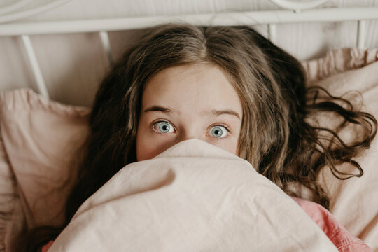 Surprised Girl With Gray Eyes Covering Mouth With Blanket At Home